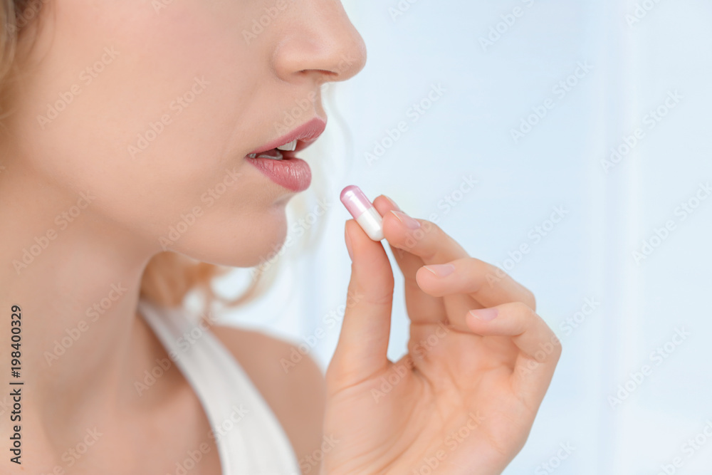 Young woman taking pill indoors Young woman taking pill indoors