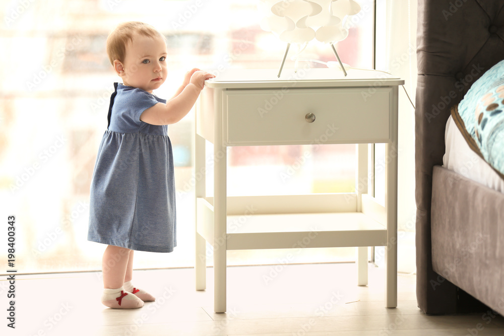 Cute baby holding on to table in bedroom. Learning to walk Cute baby holding on to table in bedroom. Learning to walk