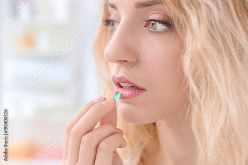 Young woman taking pill indoors