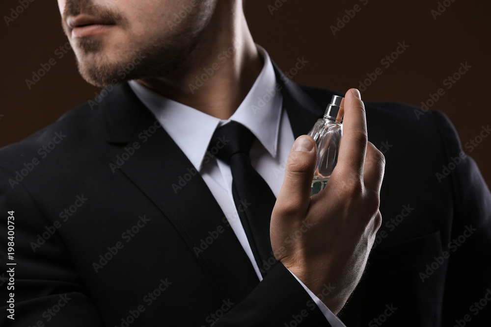 Handsome man in suit using perfume on dark background, closeup - obrazy, fototapety, plakaty 