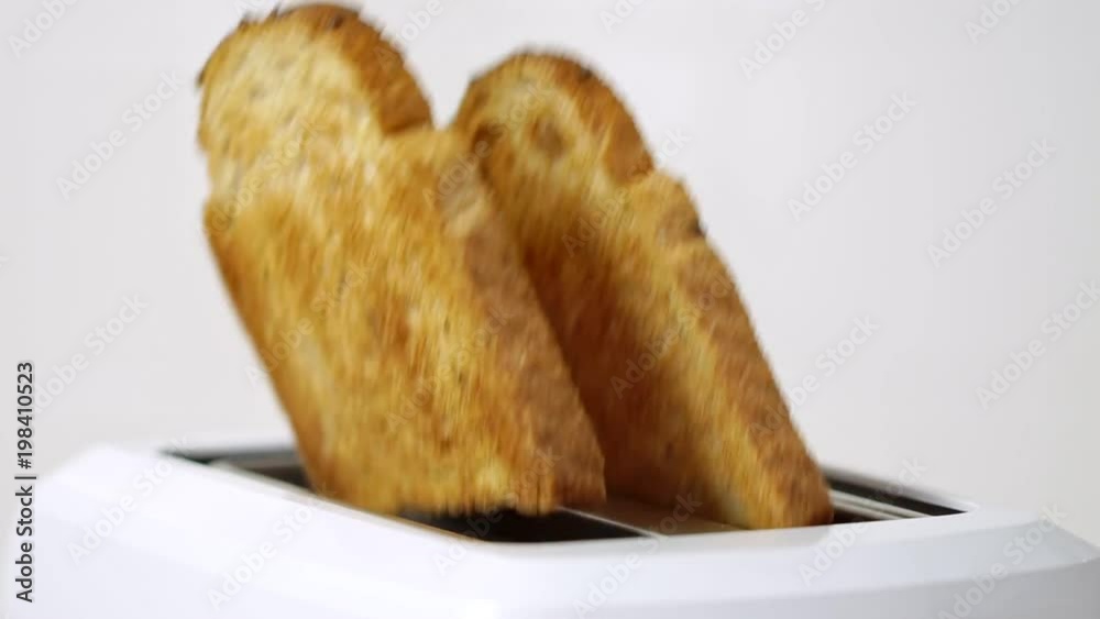 Roasted toast bread popping up from white modern toaster machine Roasted toast bread popping up from white modern toaster machine