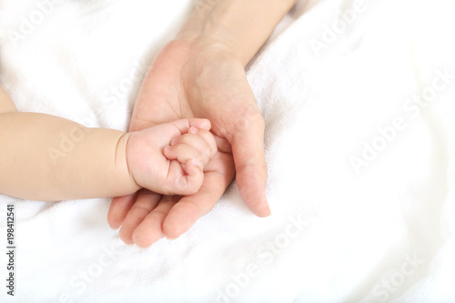小さな赤ちゃんの手を母の手で包むイメージ