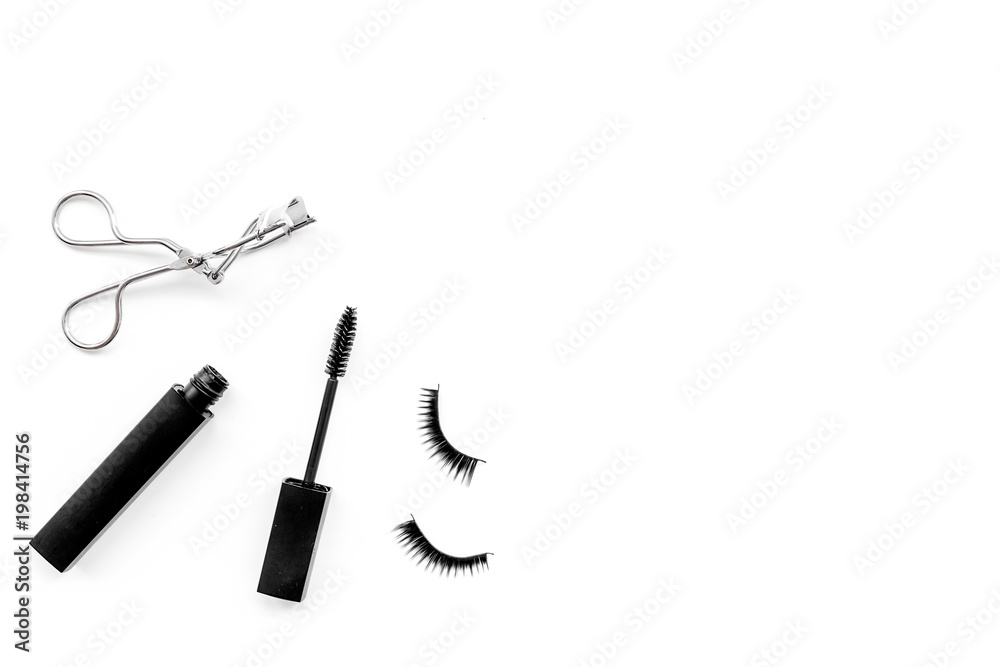 Cosmetics and tools for voluminous lashes. Mascara, false eyelashes, eyelash curler on white background top view space for text Cosmetics and tools for voluminous lashes. Mascara, false eyelashes, eyelash curler on white background top view space for text