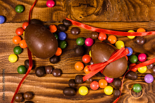 Fototapeta Naklejka Na Ścianę i Meble -  Chocolate easter eggs and multicolored candies on wooden table