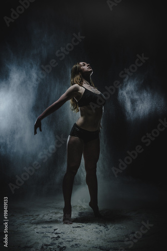 Girl dansing with flour on black background © keleny