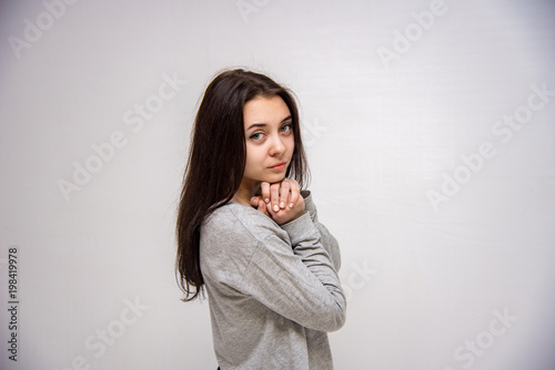 Cute brunette beautiful girl in different poses shows different emotions on different backgrounds in different clothes
