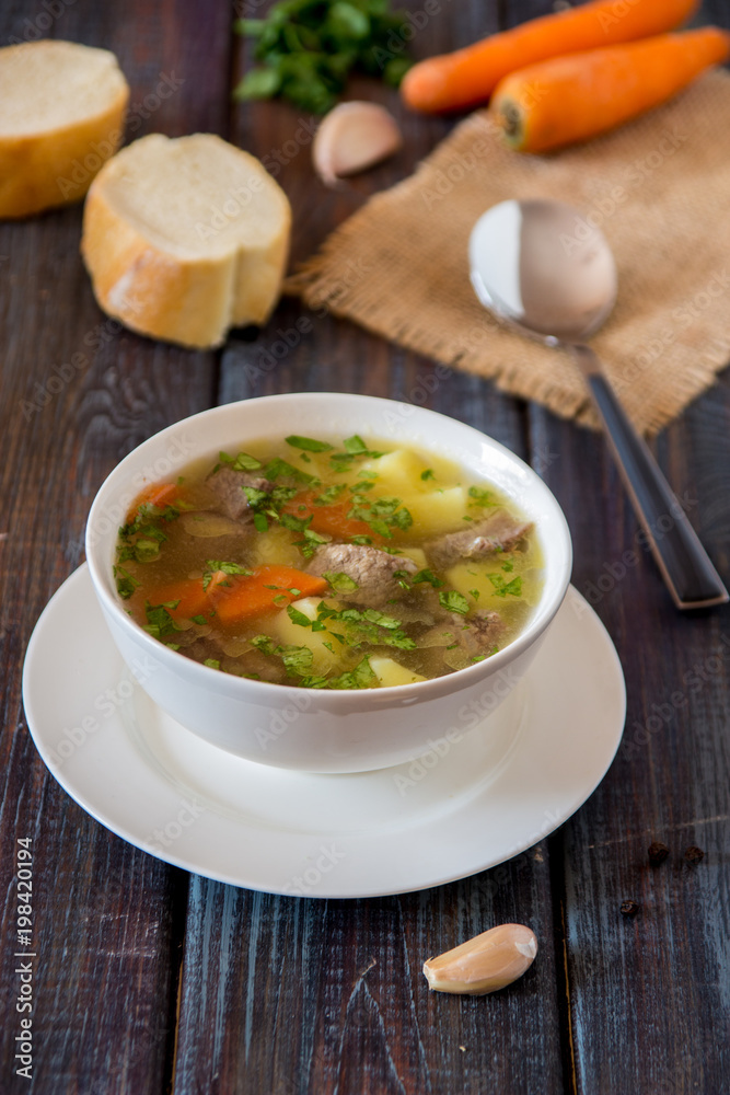 Soup with meat, potatoes and carrot. Beef soup in a white bowl
