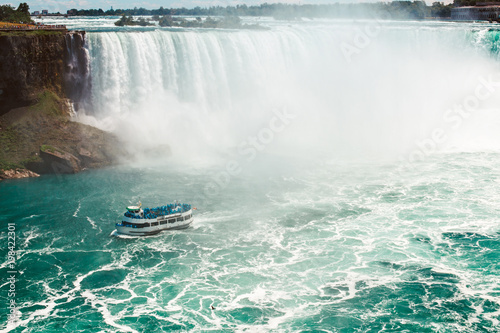 Aerial top landscape view of Niagara Falls and tour boat in water between US and Canada. Famous Canadian waterfal tourist attraction landmark on sunny day