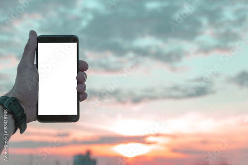 Man Holding smartphone at the sunset with isolated white screen. Empty space for text. Isolated screen for mock up. Workplace with copy space.