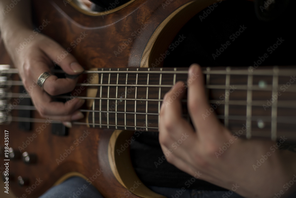 Hands of rock musician playing the electric bass guitar