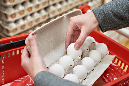 Hands with packages of white eggs in store