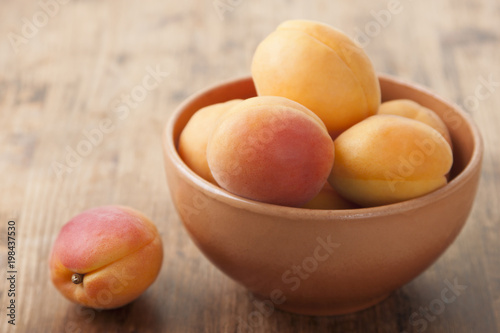 Apricots in a clay bowl on a wooden table