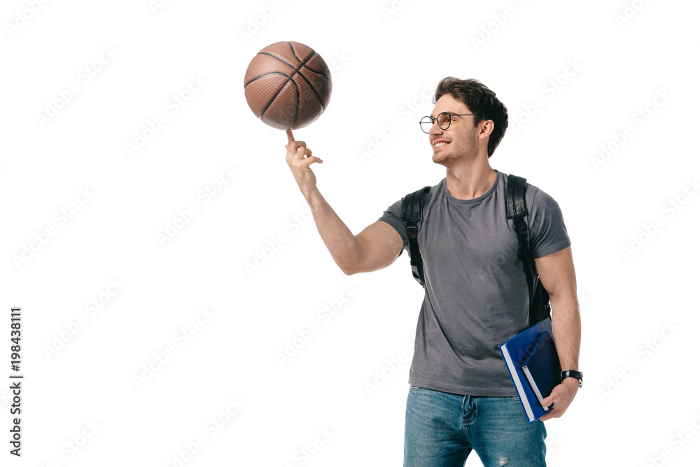 Fototapeta premium happy handsome student spinning basketball ball on finger isolated on white