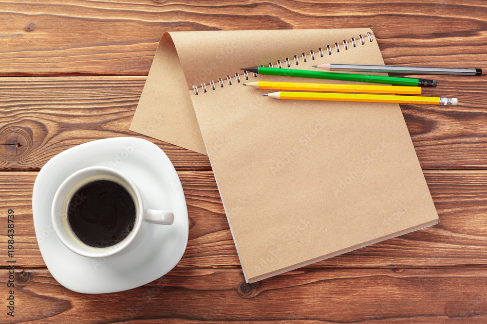 Office desk table top view. Notepad with blank pages on wooden table Office desk table top view. Notepad with blank pages on wooden table