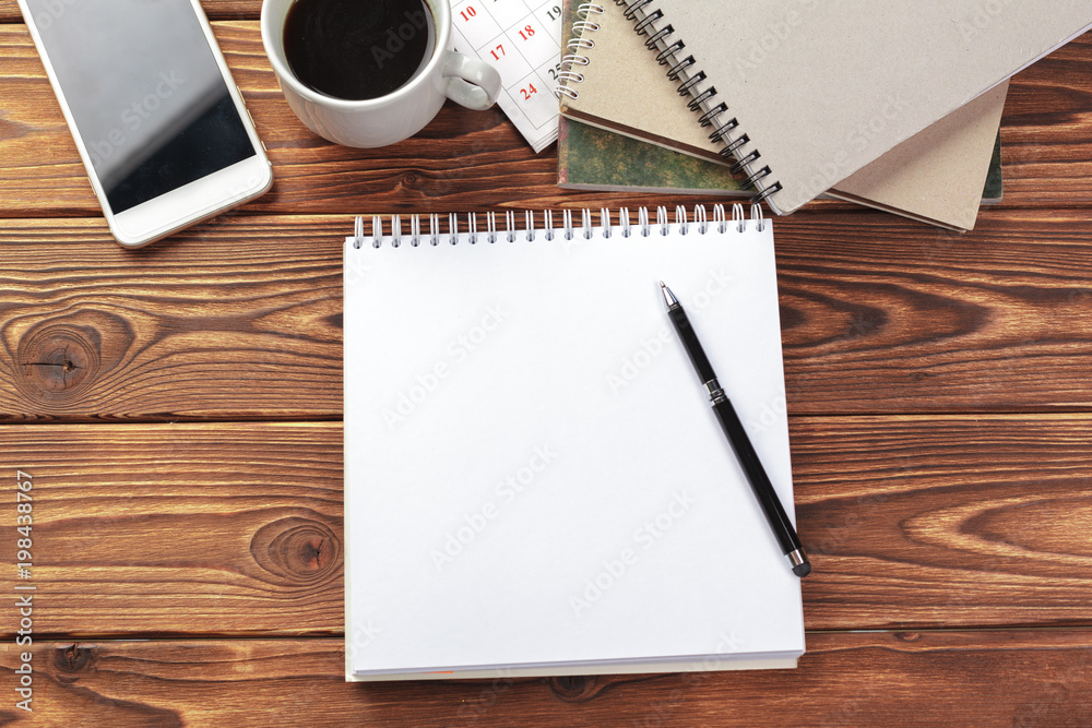Office desk table top view. Notepad with blank pages on wooden table Office desk table top view. Notepad with blank pages on wooden table