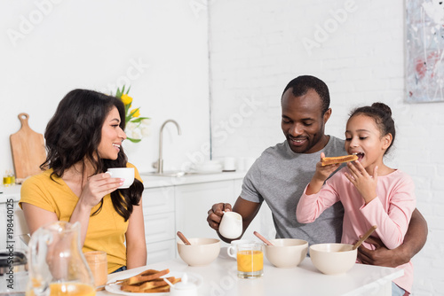 happy young family having healthy breakfast on kitchen together
