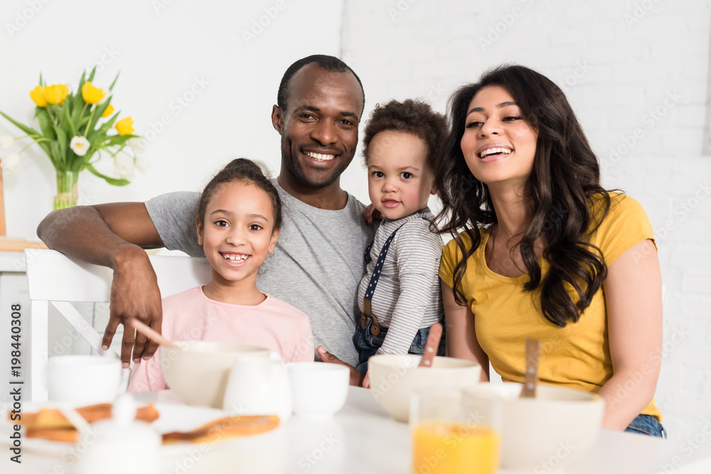 happy young family having breakfast together and looking at camera happy young family having breakfast together and looking at camera