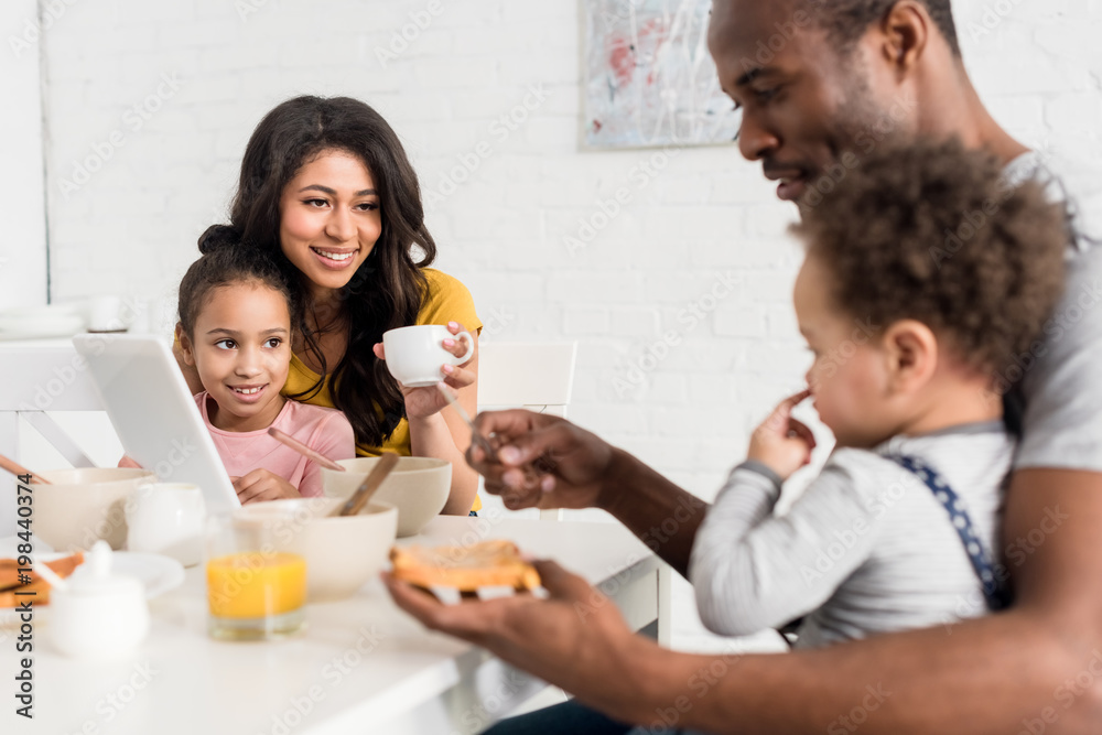 father applying peanut butter on toast for son at kitchen father applying peanut butter on toast for son at kitchen