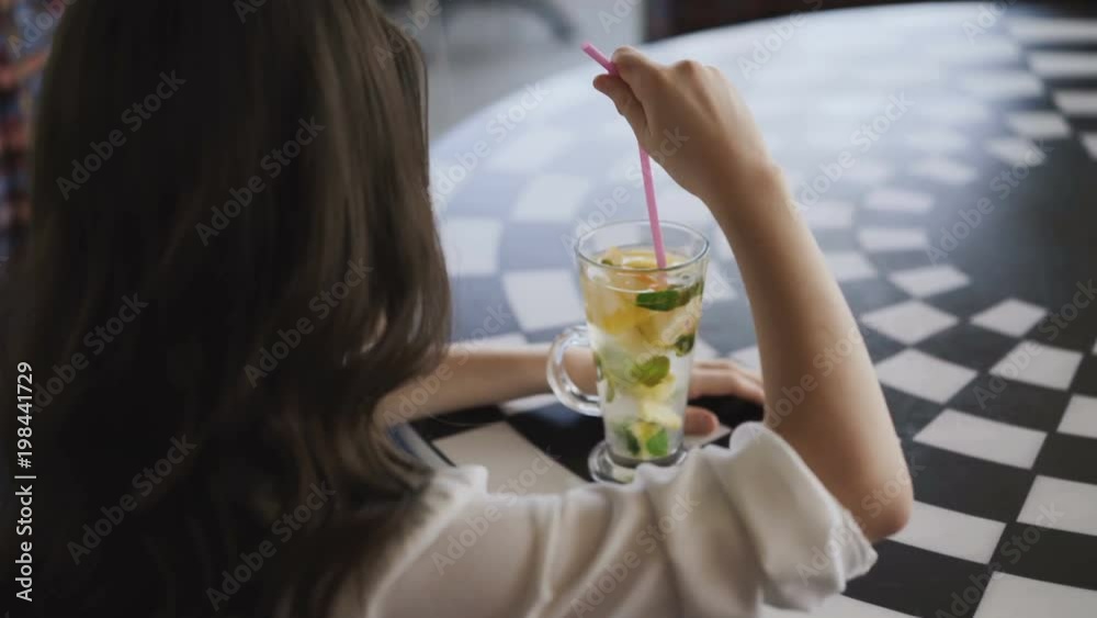 Back view of girl stirring the lemonade with tubule. 4K Back view of girl stirring the lemonade with tubule. 4K