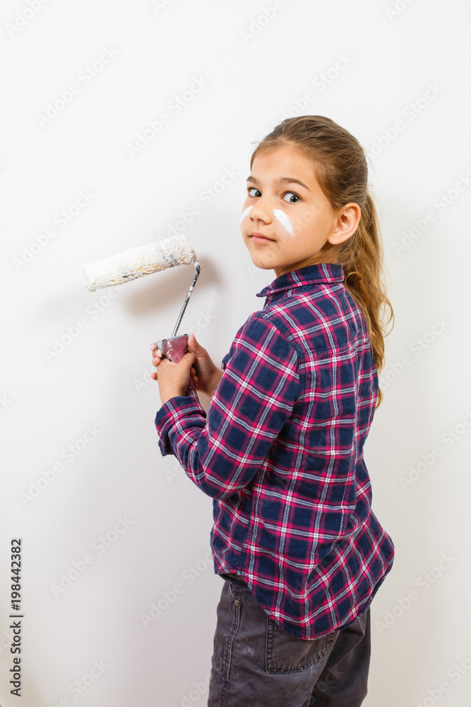 Teen girl on building ladder using a brush for painting on the white wall Teen girl on building ladder using a brush for painting on the white wall