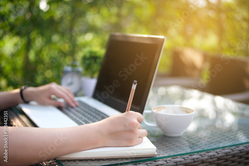 Woman writing on book, blurred nature background