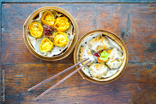 Prawn gluten free dumplings. Chicken curry steamed dumpling. A hand with chopsticks holds a piece. Wooden table background in a restaurant. Traditional Chinese cuisine. Top view with copy space