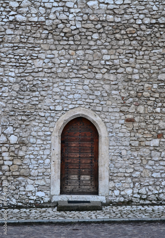Old, traditonal brown door in white castle wall Old, traditonal brown door in white castle wall