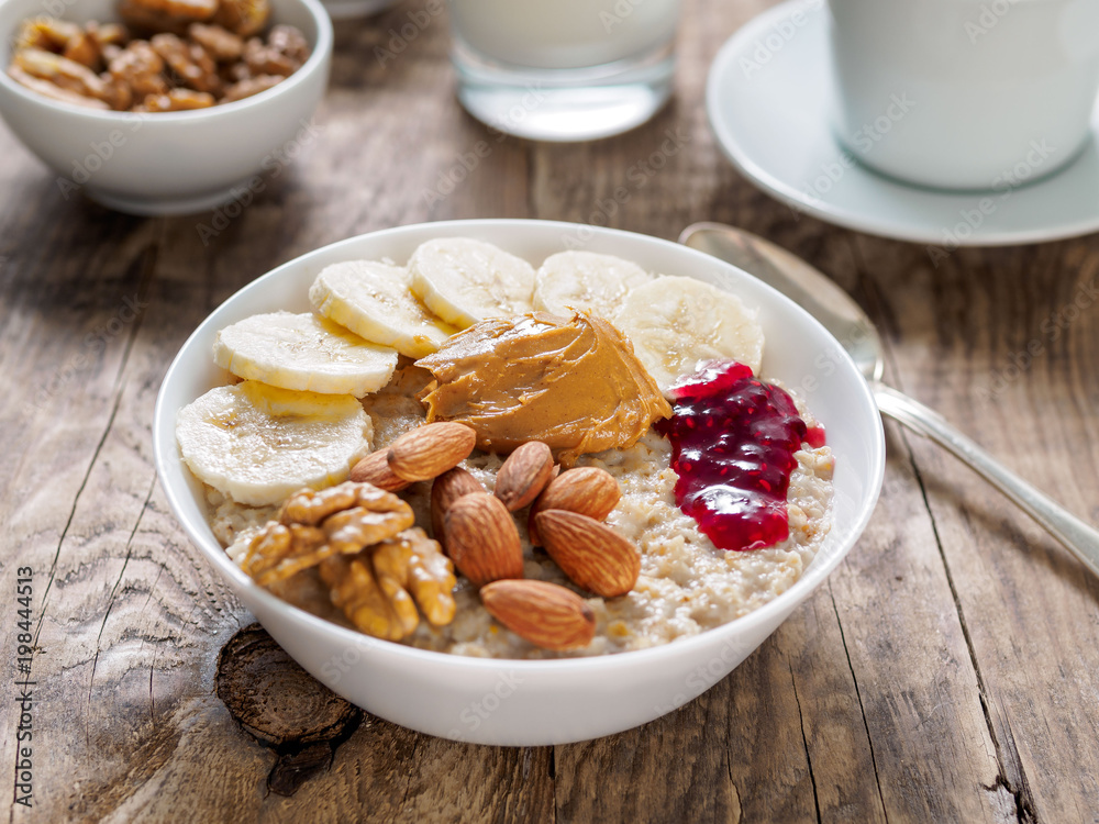A hearty and healthy oatmeal Breakfast with walnuts, almonds and peanut butter. Delicious food, a source of slow carbohydrates.
