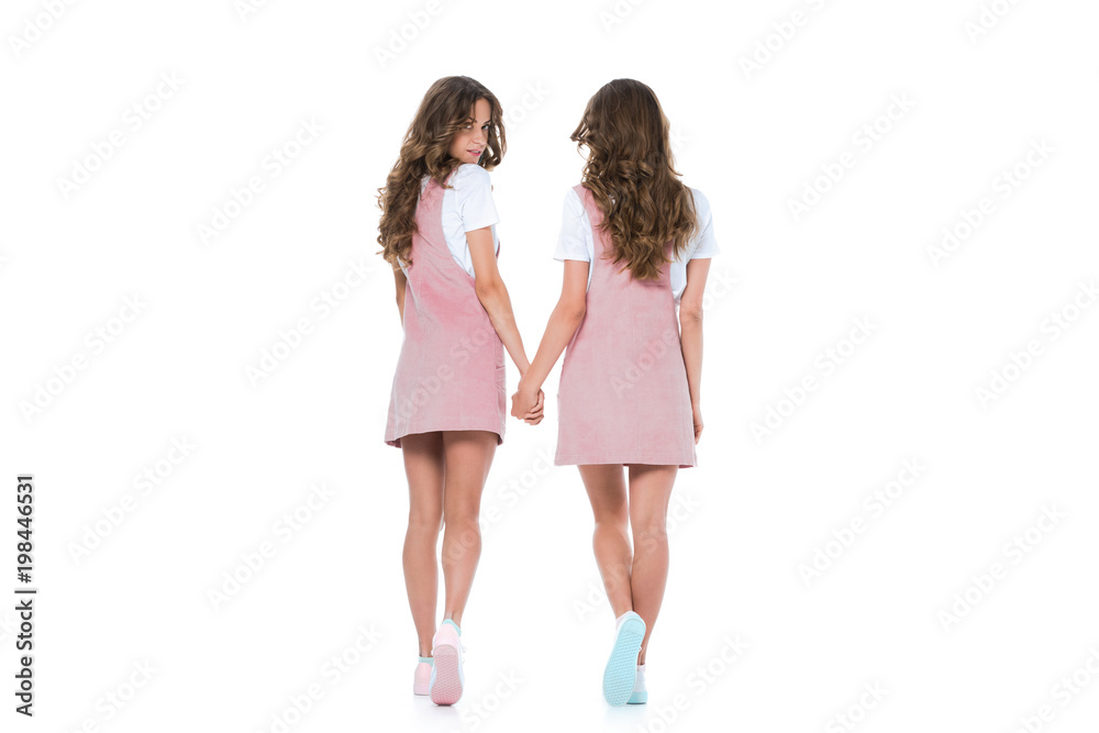 back view of young twins holding hands isolated on white back view of young twins holding hands isolated on white