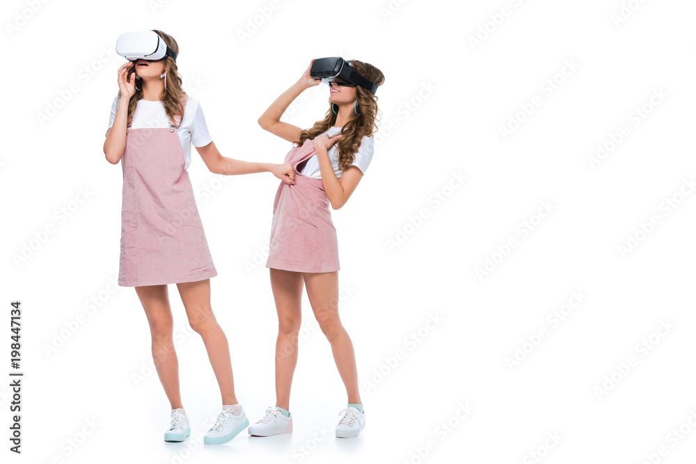 surprised twins watching something in virtual reality headsets isolated on white surprised twins watching something in virtual reality headsets isolated on white