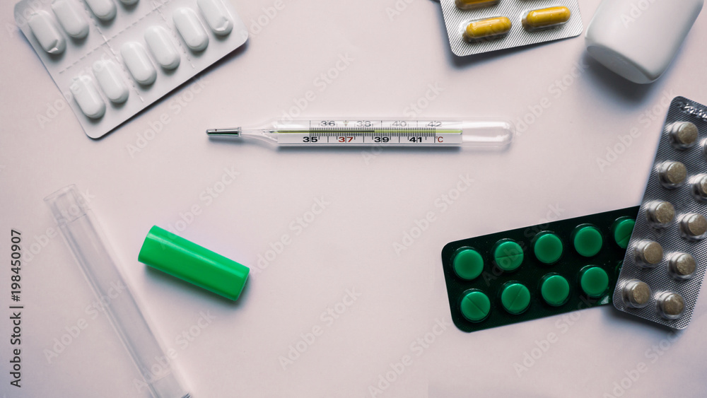 Medication pills and thermometer on white background Medication pills and thermometer on white background