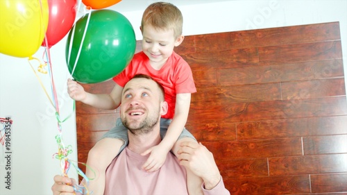 Little boy on the daddy's kneck with colored ballons photo