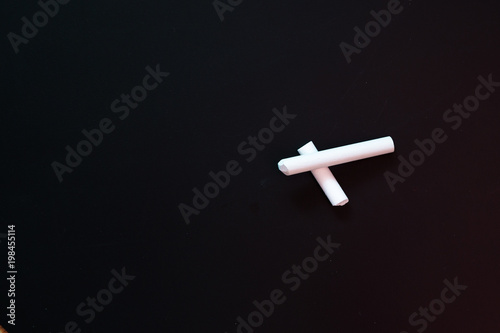 Two pieces of white chalk lie on a chalk writing board.