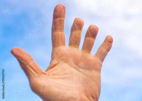Male hand with clipped fingers against the blue sky