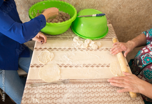 Woman and daughter rolls out dough in the kitchen photo