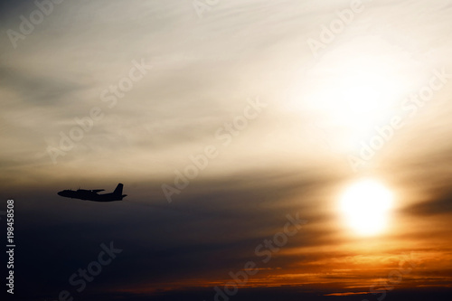 plane flying at sun in sunset sky. airplane in the air. transportation concept with space for text.  Silhouette of a big passenger or cargo aircraft in sun light and clouds.