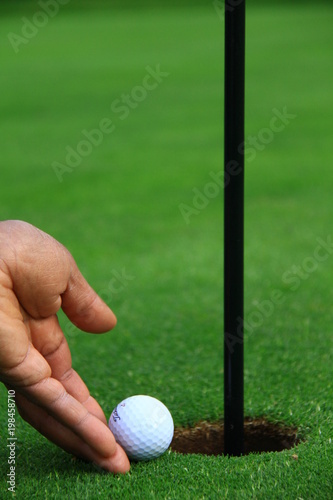 hand pushing golf ball into the hole stock photo
