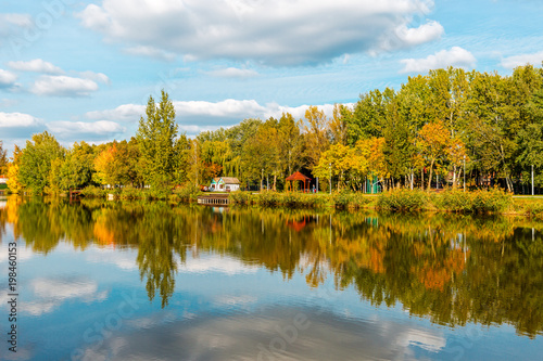 Beautiful lake with mirror reflections in clear water on sunny day. Tranquil landscape with lake, cloudy sky, and trees reflected symmetrically in the water. Salt lake (Sosto) Nyiregyhaza, Hungary