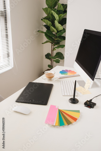 Creative designer workplace with desktop computer, stylus and tablet.