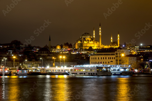 Illuminated Istanbul at night. Turkey. Night view of historical part of Sultanahmet area Famous mosques, pier with boats, cafes, bars and shops. Bosphorus river with boats.