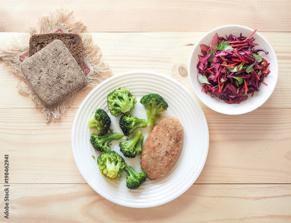 Cutlet and broccoli on white plate on light wooden background. Cutlet and broccoli on white plate on light wooden background.