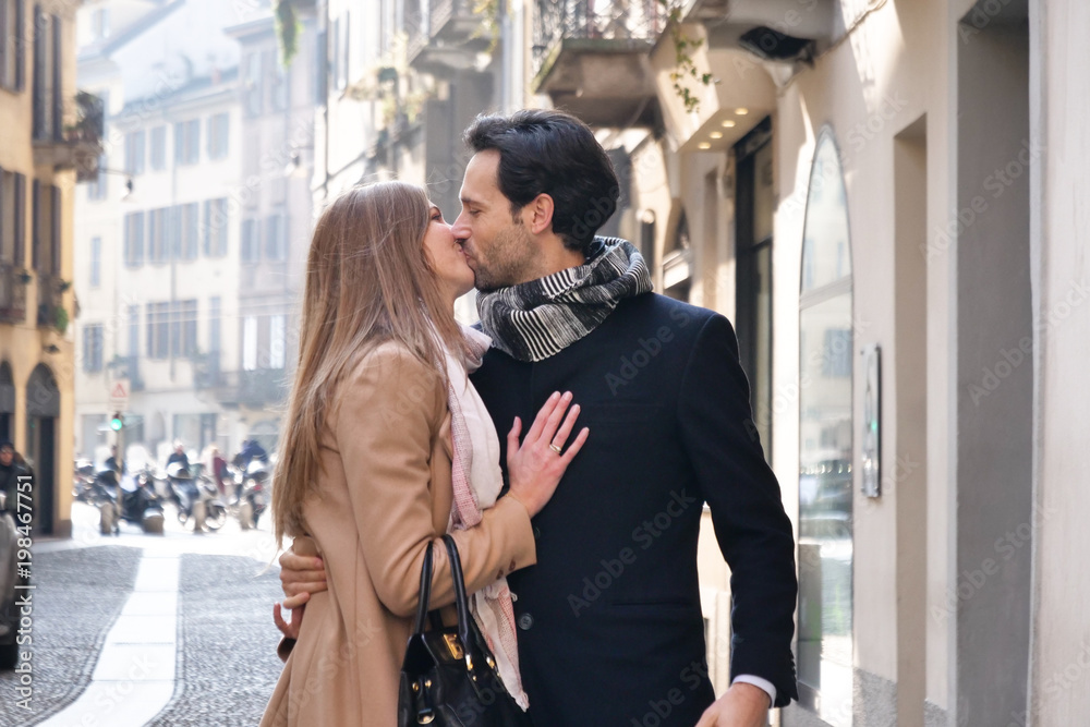 A couple of lovers walk through the city, hand in hand in sign of their love. Concept of: love, valentine, happiness, urban A couple of lovers walk through the city, hand in hand in sign of their love. Concept of: love, valentine, happiness, urban