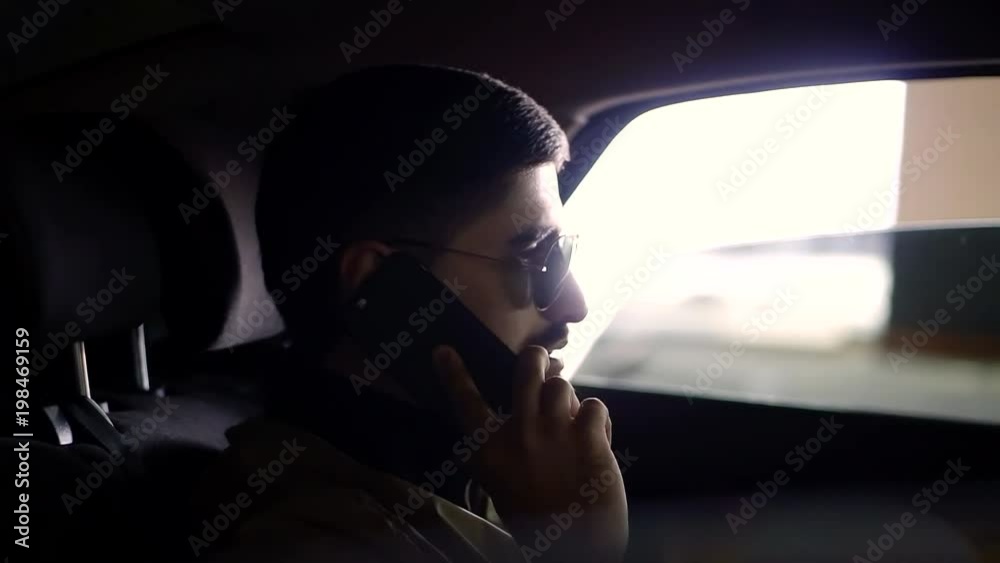 a man who looks like a producer talks on a smartphone in a vehicle, he holds in his hand an expensive phone a man who looks like a producer talks on a smartphone in a vehicle, he holds in his hand an expensive phone