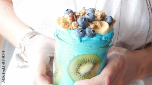 female hands holding blue majik, summer spirulina smoothie, showing, giving, offering photo