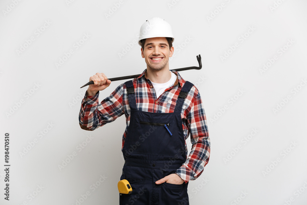 Smiling male builder in protective helmet holding crowbar Smiling male builder in protective helmet holding crowbar