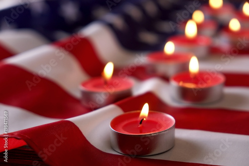Mourning candles burning on USA American national flag background. Memorial weekend, patriot veterans day, 9/11 National Day of Service & Remembrance. Moment of silence concept. Close up, copy space. photo