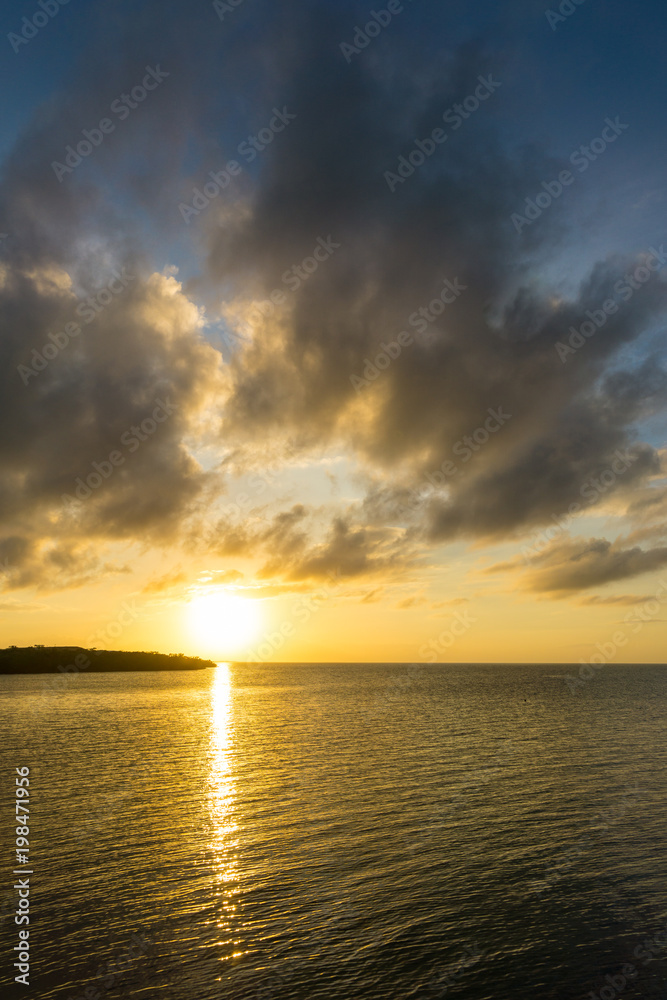 USA, Florida, Orange sunset reflecting in silent ocean water with some clouds