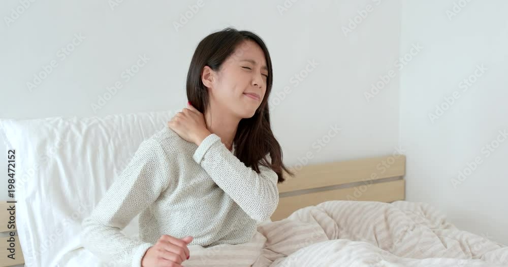 Woman feeling shoulder pain and sitting on bed Woman feeling shoulder pain and sitting on bed