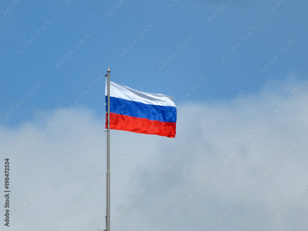Russian flag on the background of the cloudy blue sky. National flag of Russia over Red square in Moscow Russian flag on the background of the cloudy blue sky. National flag of Russia over Red square in Moscow
