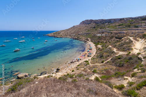 Fototapeta Naklejka Na Ścianę i Meble -  Beautiful azure blue water of Selmun beach in the summer time, in Maltese Imgiebah Bay, Il-Mellieha, Malta, June 2017